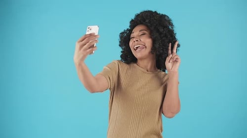 An Attractive Darkskinned Girl Takes a Picture of Herself on the Front Camera of a Smartphone The