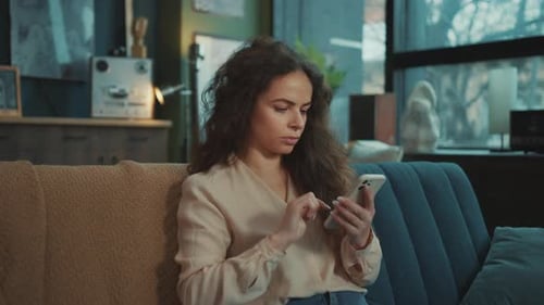 Woman Using Phone While Sitting on Couch Indoors
