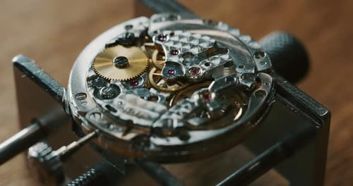 Slow motion close up of a professional watchmaker repairer working on a luxury mechanism watch gea