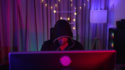 Hooded Figure Working at Computer at Night
