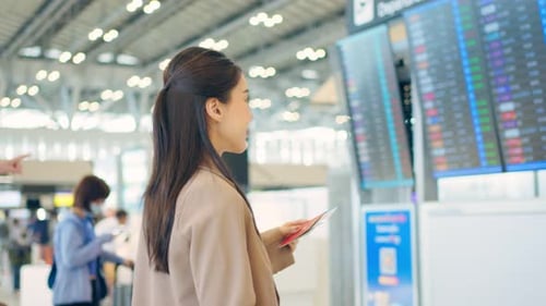 Asian young woman passenger checking departure boarding pass in airport.