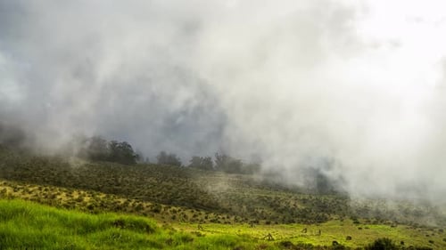 Time lapse of creeping clouds moving over a misty mountain landscape