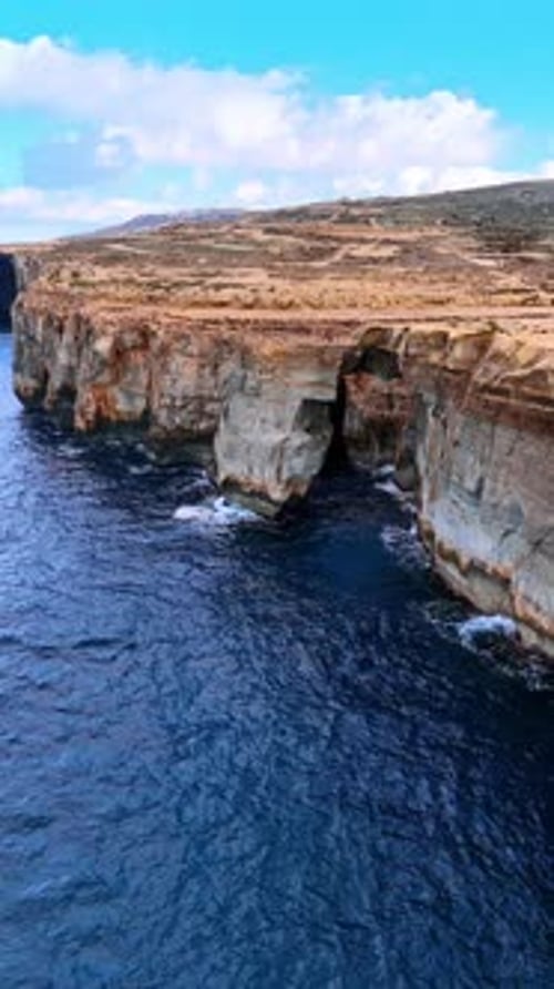 Rocky coast of Malta, Europe. Approaching high cliffs at the shore of the Mediterranean Sea.