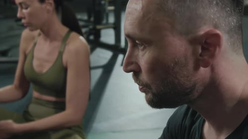 Man Drinking Water from Bottle while Resting after Training in Gym