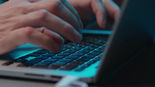 Hacker-Hände tippen auf moderner Laptop-Tastatur im dunklen Raum mit Dramatisch türkisfarbenem Lichtkonzept von