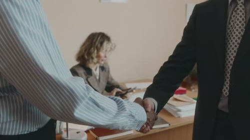 Businessmen Shake Hands In Cluttered Office Setting