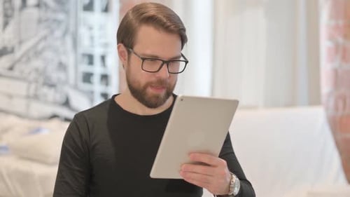 Man Celebrates Success While Using Tablet