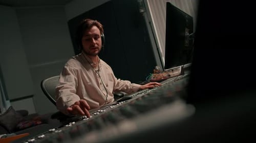 Energetic audio engineer producer working in recording studio mixing tracks on console and hit maker