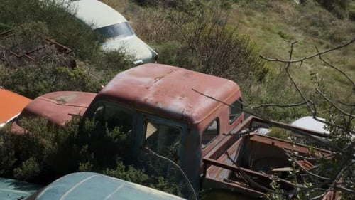 View of a vintage red truck in a car junkyard.