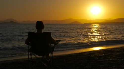 Woman Relaxing on Beach Watching Setting Sun