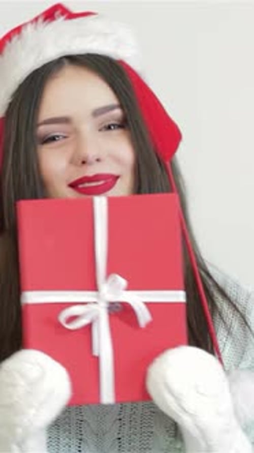 Woman Holding Christmas Present Wearing Santa Hat