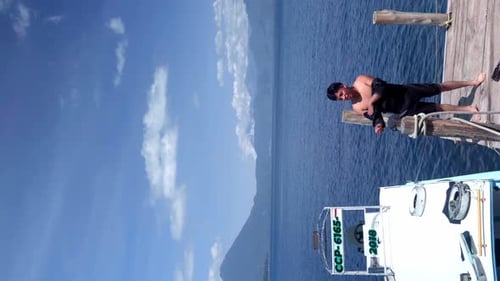 Man putting on a wetsuit on a lake pier