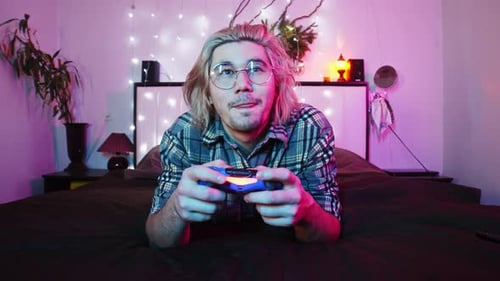 Young Adult Playing Video Game on Bed
