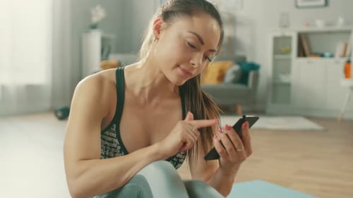 Young Woman Uses Phone After Workout at Home
