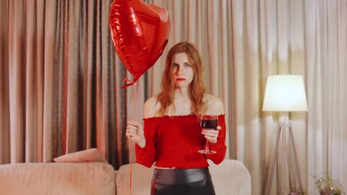 Woman Holding Heart Balloon Drinks Wine Indoors