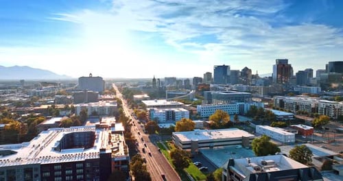 Long straight highway crosses the cityscape. Bright sun dazzles the scenery of Salt Lake City