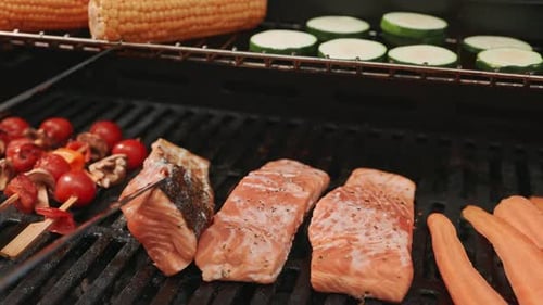The Chef Carefully Turns the Salmon Fillets on the Grill with Metal Tongs