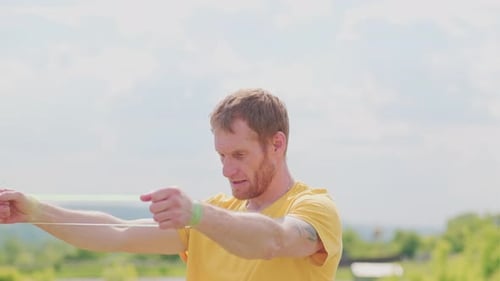 Um esportista profissional com uma camisa amarela está segurando um expansor de elástico. Ele parece focado e