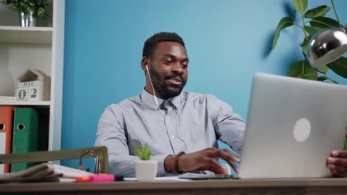 A Young Professional Engaged in Working at a Laptop in a Sleek Modern Office Space
