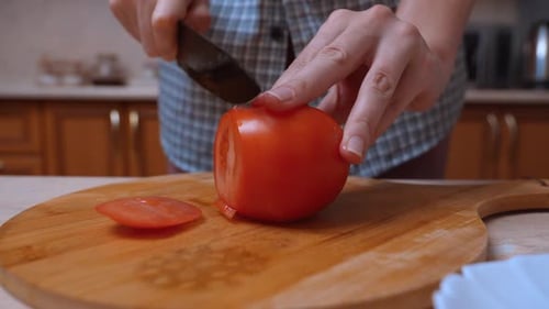 Slicing a Fresh Tomato on Wood Cutting Board
