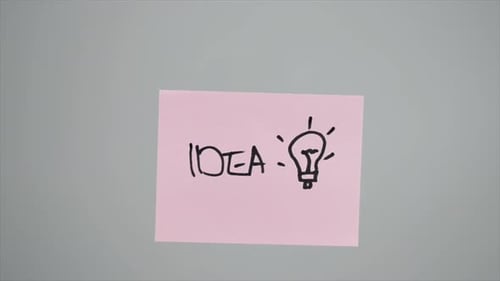 Hand Draws Idea and Lightbulb on Sticky Note