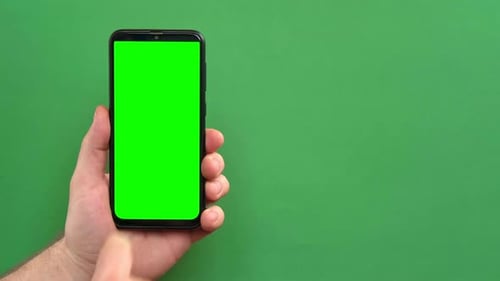 Junger Mann bedient Smartphone mit grünem Bildschirm auf grünem Hintergrund Gestenpackung Männliche Hand Berühren