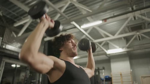 Young Man Performing Seated Overhead Press with Dumbbells in Gym