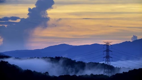 A high voltage tower and a sea of raging, tumbling clouds on a summer morning.