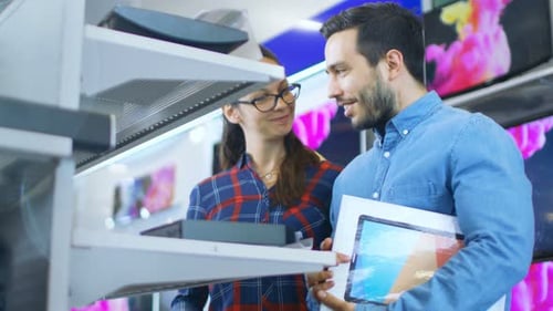 Beautiful Young Couple in the Electronics Store Browsing, Looking for Newest Gadgets, Tablets and P