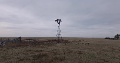Rustic Windmill Towering Over Barren Plains on Cloudy Day