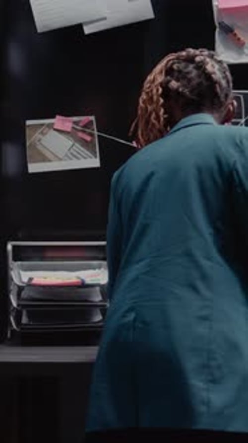 Investigator Analyzing Evidence on Case in Dark Office