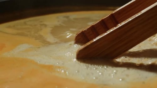 Noodles Stirred in Broth with Wooden Tongs