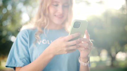Woman Uses Smartphone in City Park on Sunny Day