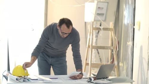 Architect reviews blueprints at construction site office