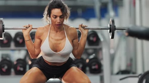 Muscular Woman Performing Barbell Squats at the Gym