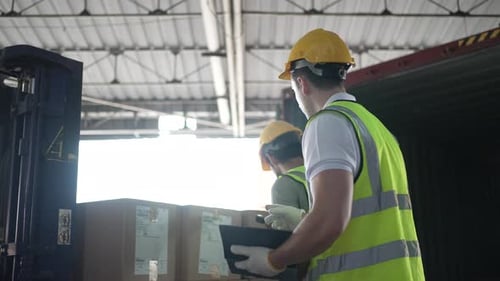 Blue collar workers are working at warehouse.