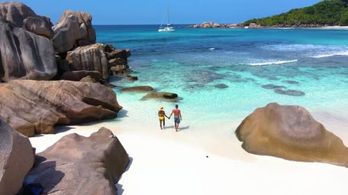 Strolling Hand in Hand on a Pristine Beach in Seychelles Surrounded By Stunning Turquoise Waters