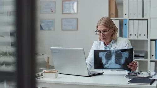 Woman Doctor Analyzes X-Ray in Bright Office