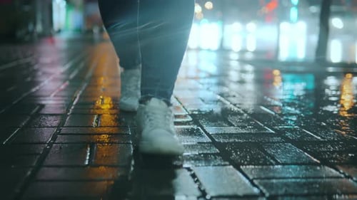 Closeup of a Girl's Legs Walking in Front of the Camera on Wet Paving Stones