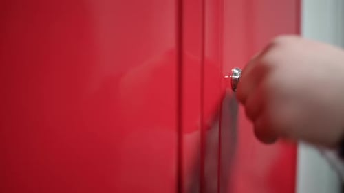 Closeup A Woman's Hand with a Key Opens a Locker Door in a Locker Room