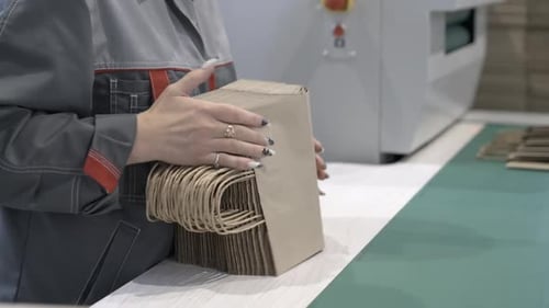 Un employé de l'usine vérifie la qualité des sacs à provisions en papier empilés