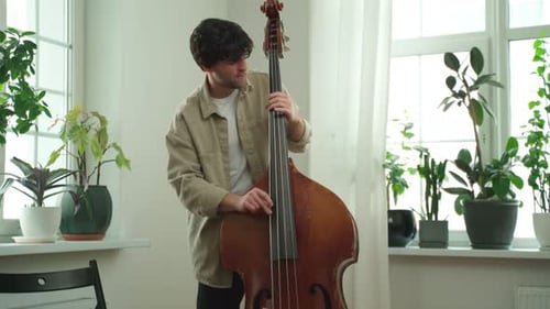 Young Adult Plays the Contrabass in Bright Room