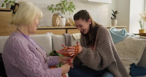 Senior Woman Shows Adult Female How to Knit
