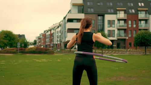 Rear View Active Woman Twists Her Booty and Hips During Workout with Hula Hoop