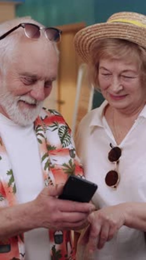Elderly Couple Looking at Phone on Vacation
