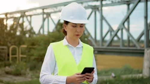 Woman Engineer Using Smartphone Inspecting Bridge Construction