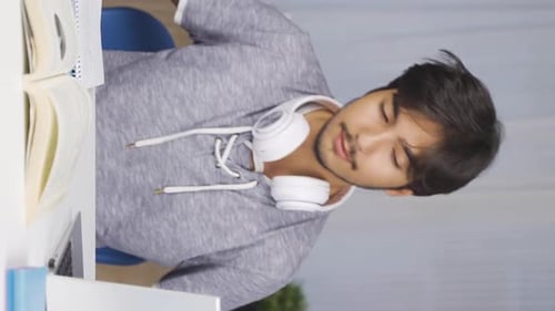 Young Man Studying at Desk with Laptop and Book