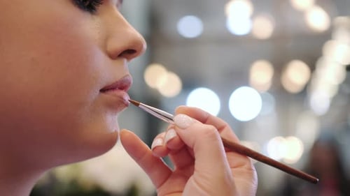 Professional Make Up Artist Applying Lipstick on Female Lips