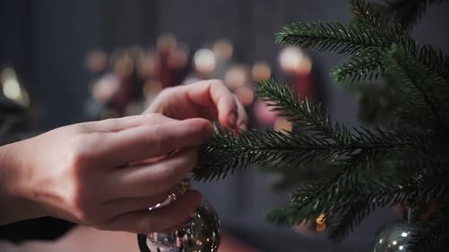 Hands Decorating Christmas Tree with Silver Ornaments