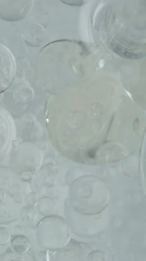 Vertical video. Top View, Oil Poured into Water and Splitting into Multiple Spheres and Bubbles.